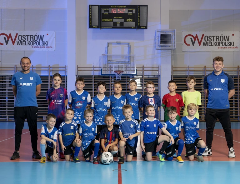 Uśmiechnięci zawodnicy Akademii Krecika z kadrą trenerską w hali w Ostrowie Wielkopolskim